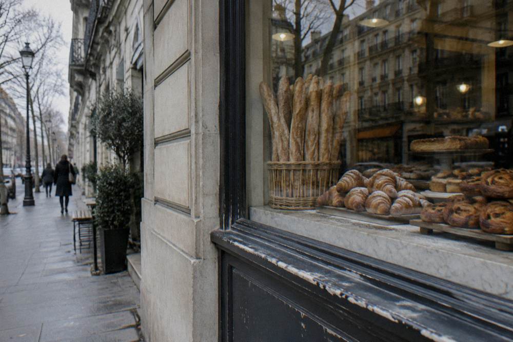 Fresh baguettes and pastries displayed in the window of a small Paris bakery