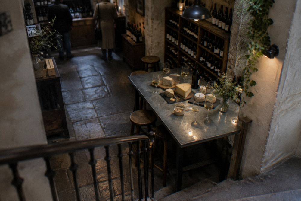 A row of cheese wedges and filled wine glasses arranged on a cellar tasting table