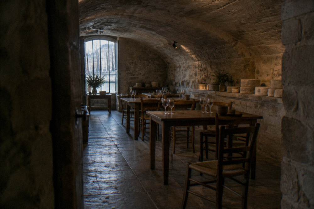 A quiet cellar room with wooden tables set with tasting glasses before guests arrive