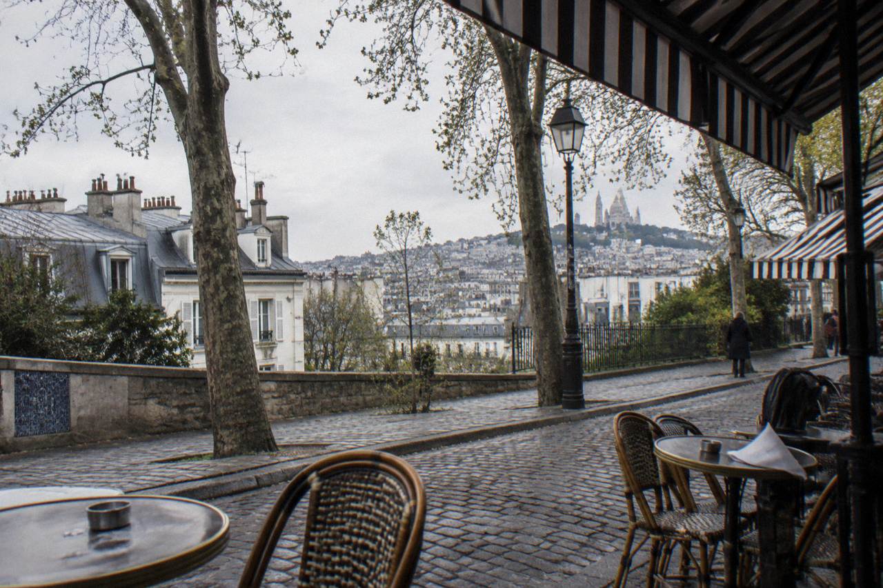 Cafe tables and striped awnings along a cobblestone Montmartre street