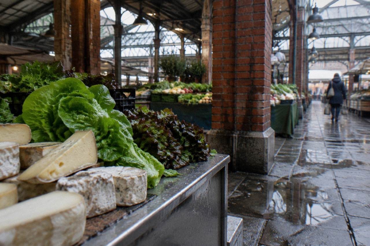Stalls of cheese and fresh produce inside a covered Paris market hall
