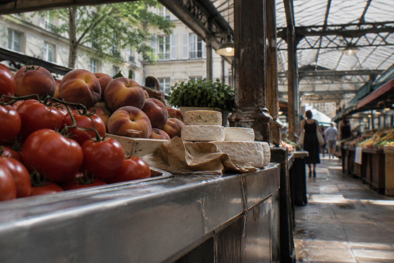 Colorful produce stalls and cheese counters inside a covered Paris food market