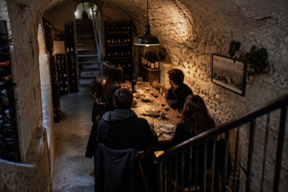 Guests in smart casual clothing seated around a tasting table with wine glasses and cheese boards