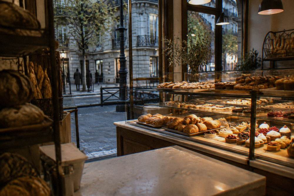 A bakery counter with trays of pastries behind glass