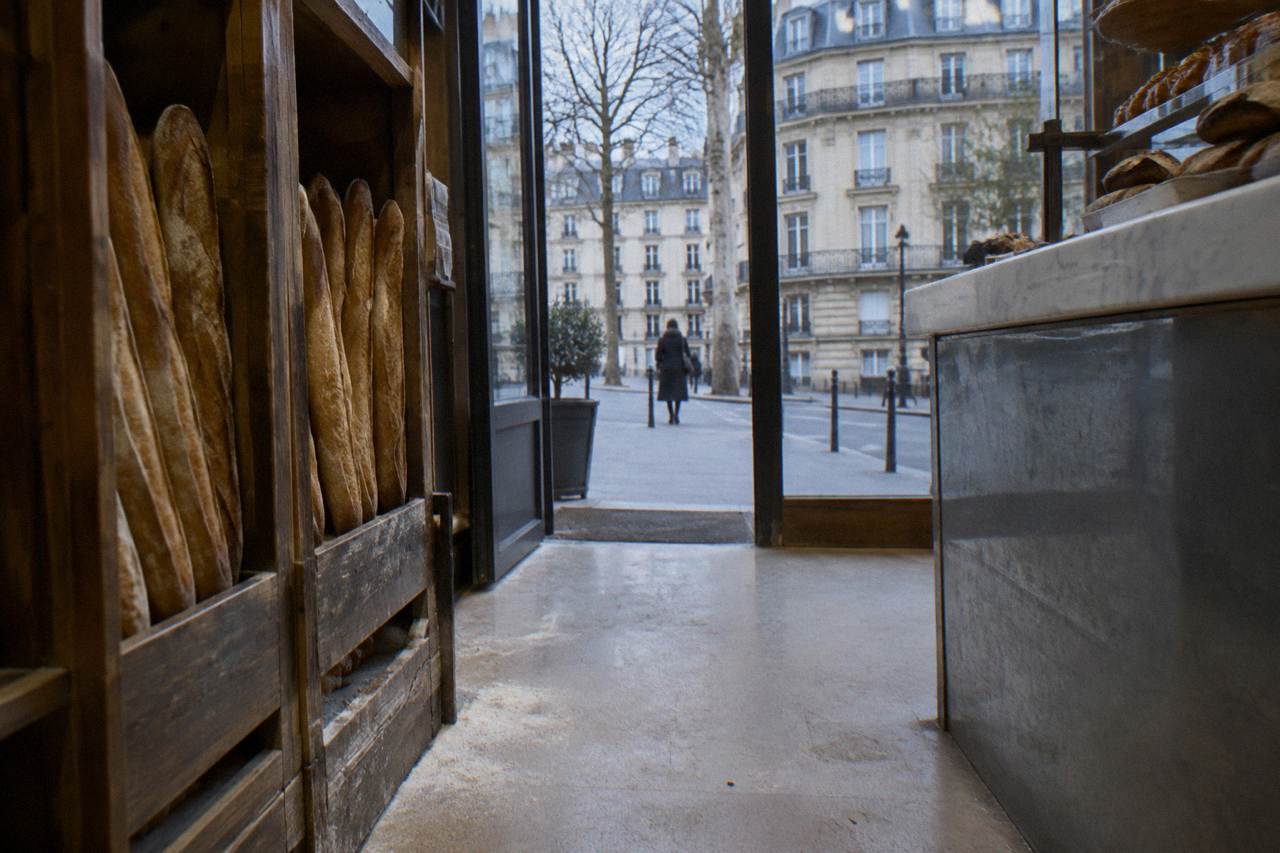 Fresh baguettes standing upright in wooden racks inside a Paris bakery