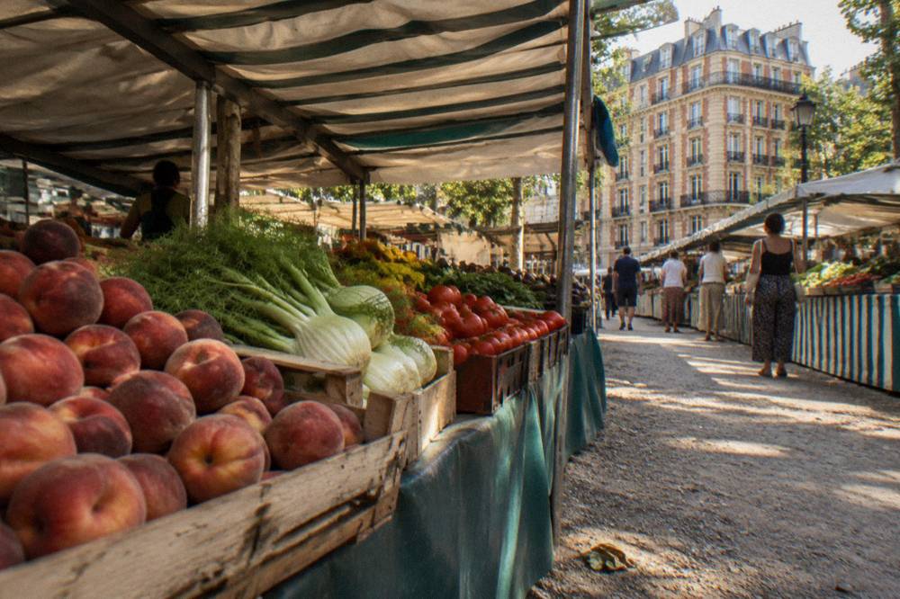 A market stall in Paris piled with fresh produce under a canvas awning
