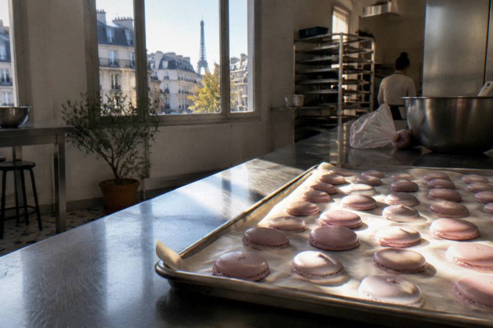 Piped macaron shells resting on a baking tray in a kitchen