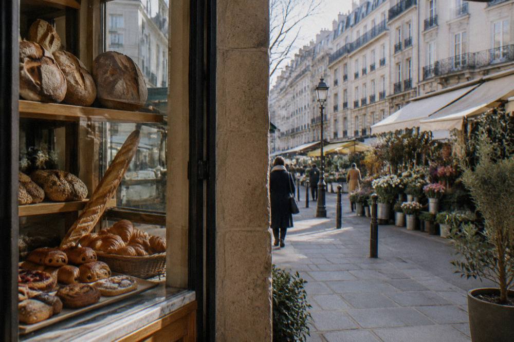 Assorted bread loaves and pastries displayed in the window of a Paris bakery
