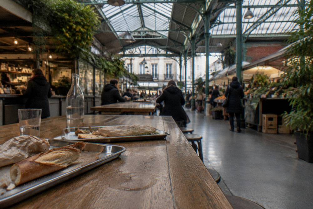 Long communal tables inside a busy Paris food hall at midday
