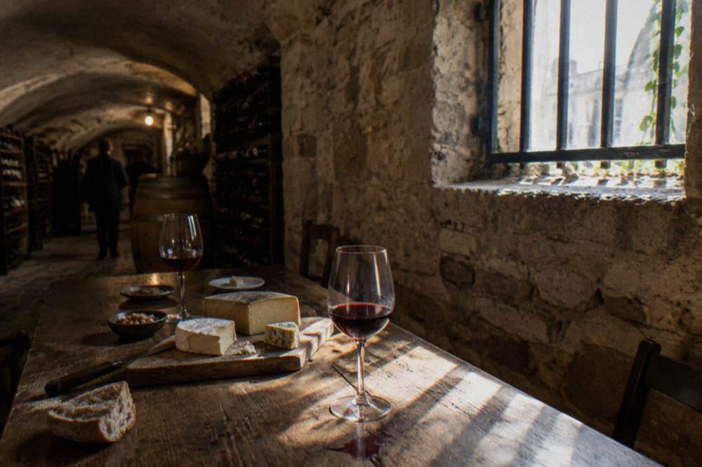 Assorted French cheeses and glasses of red wine arranged on a cellar table