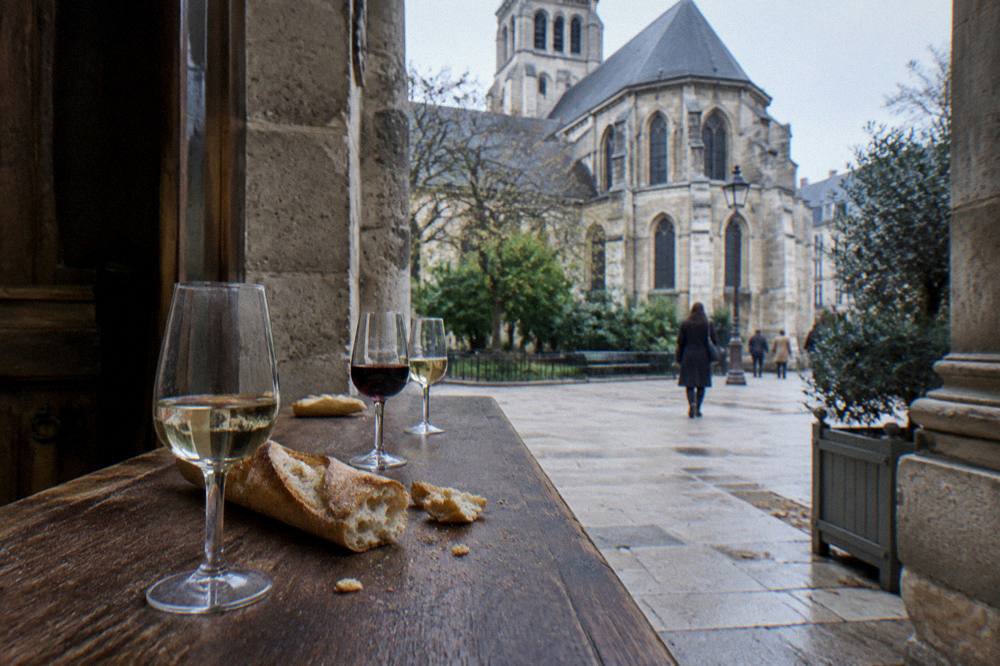 Small group of tasting glasses lined up on a wooden counter beside bread