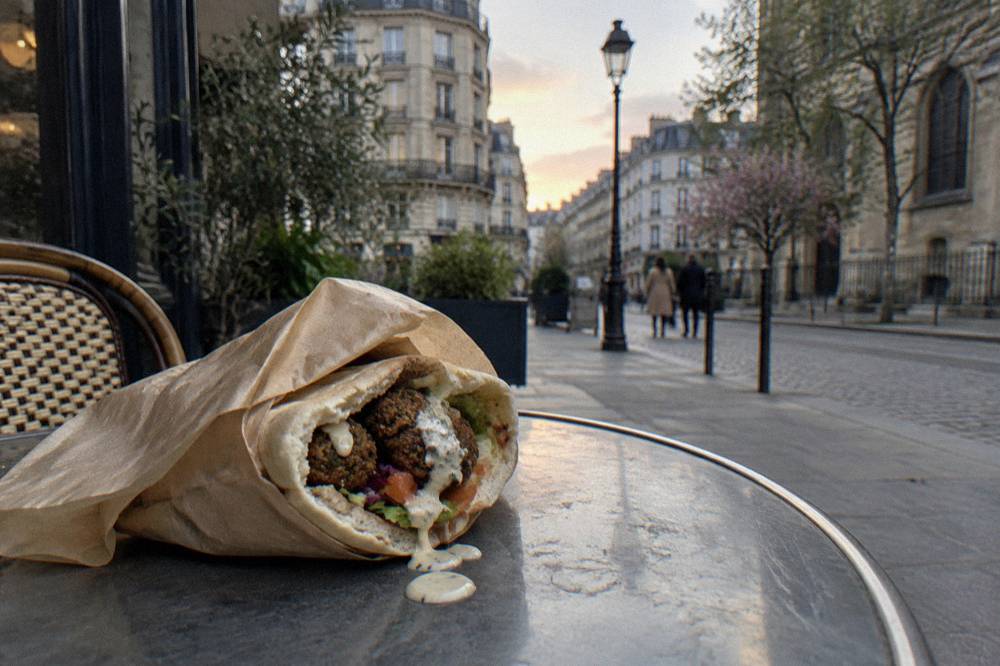 Wrapped falafel sandwich held in paper on a Paris street
