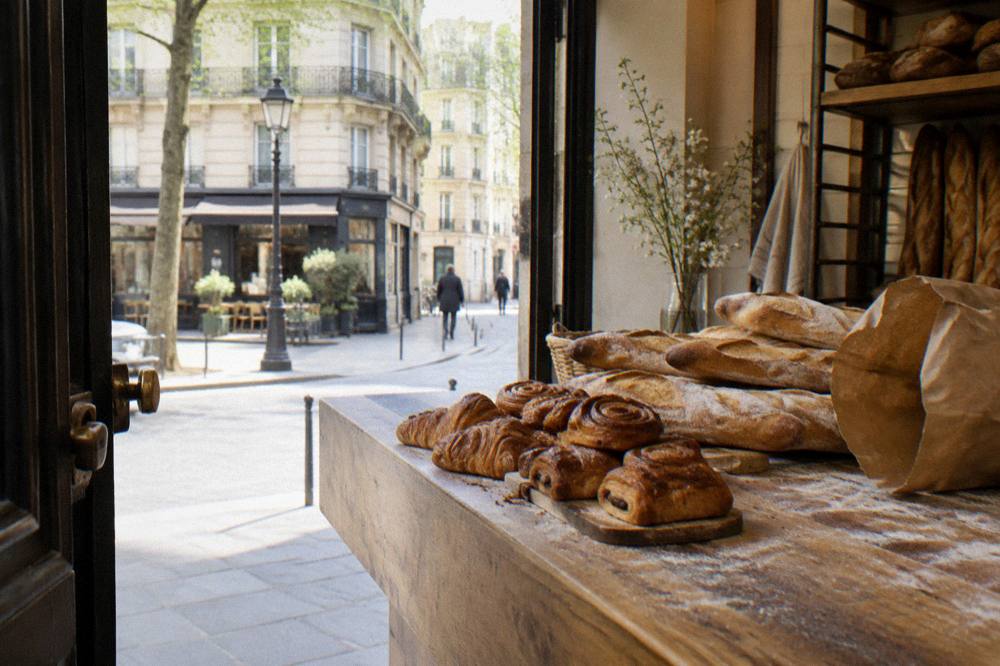 Fresh bread and pastry lined up on a wooden bakery counter