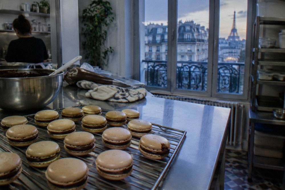 Finished macarons sandwiched with ganache fillings on a cooling rack