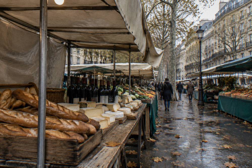 Wooden market table with baguettes, cheeses and bottles of wine arranged for a tasting