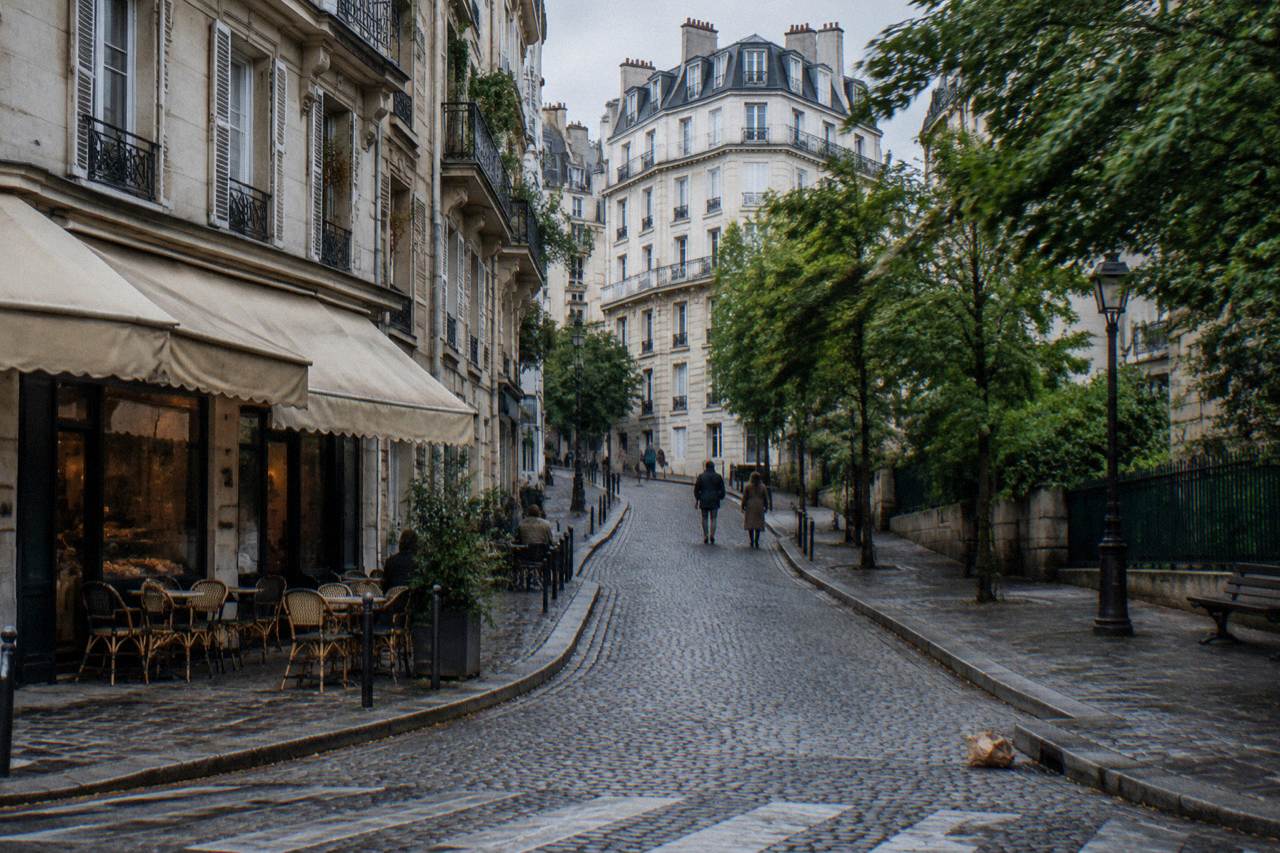 Slope of a Paris hill neighbourhood with bakery awnings and cafe terraces along a cobbled street