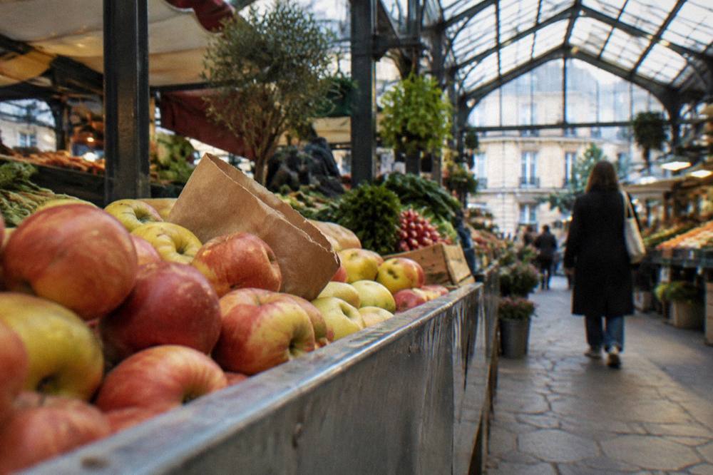 Hands selecting apples at a market stall in early morning light