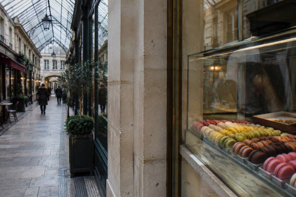 A display of colorful macarons arranged in rows in a glass pastry case