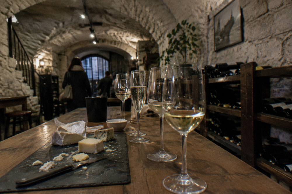 Glasses of white wine and Champagne lined up on a tasting table with a slate cheese board
