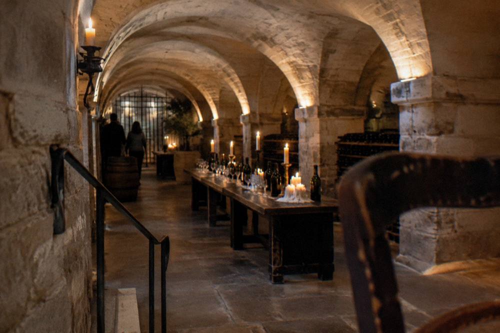 Vaulted stone wine cellar with candles, bottles and a set tasting table