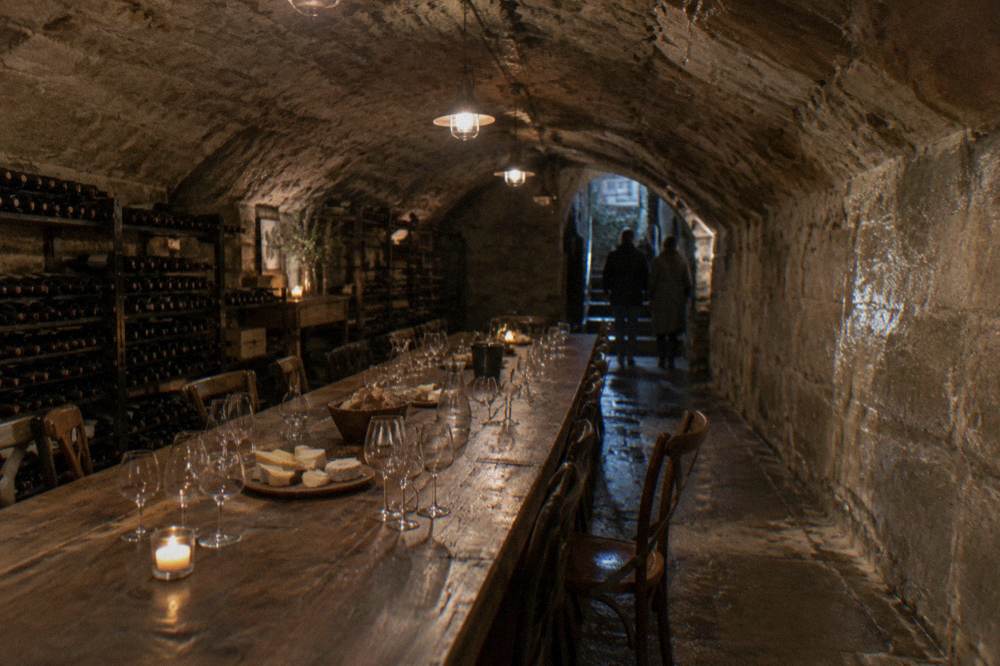 A stone-vaulted cellar room with a long table set for a wine tasting